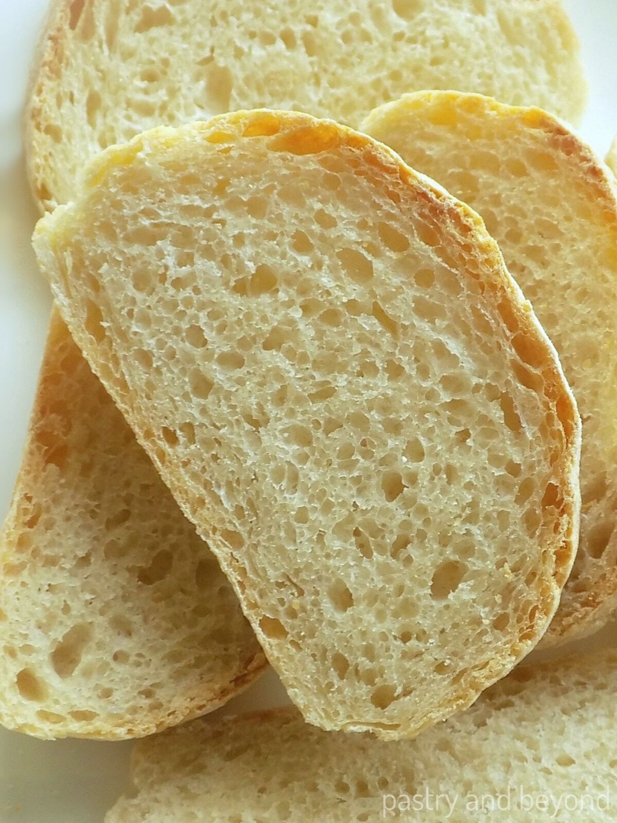 Homemade no knead bread slices on a white surface.