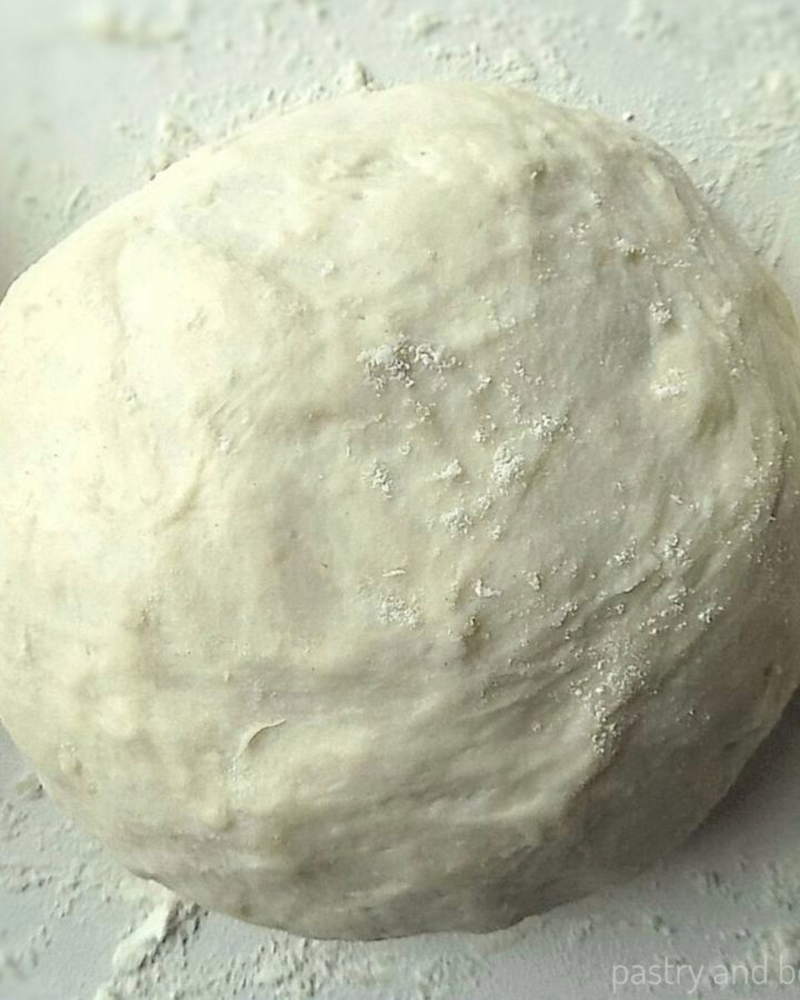 Pizza dough that is made by hand and rolled into a ball on a floured surface.
