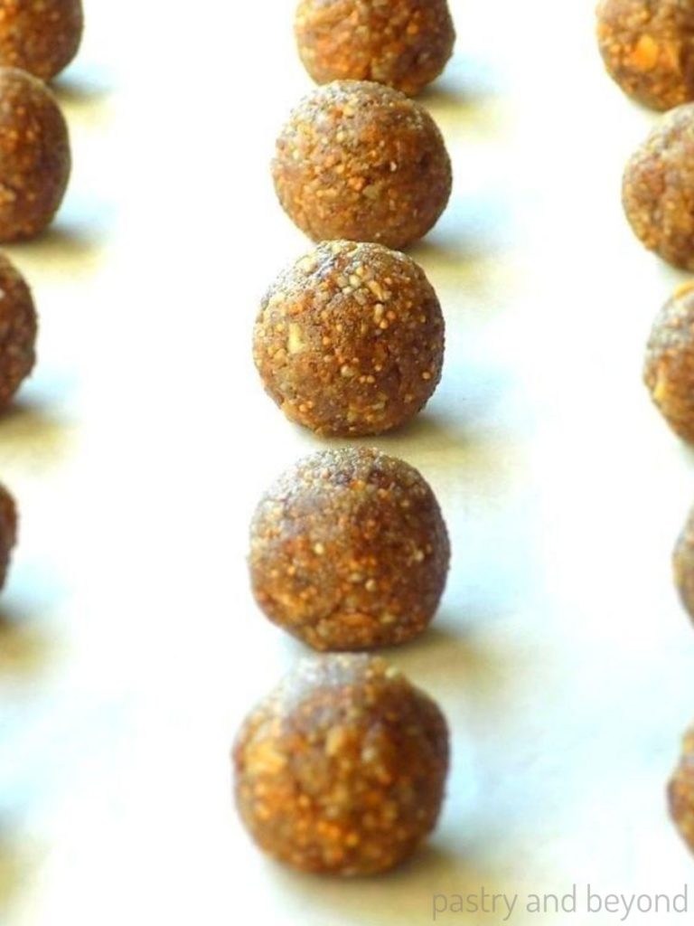 Fig and walnut energy balls in a row on a parchment paper.