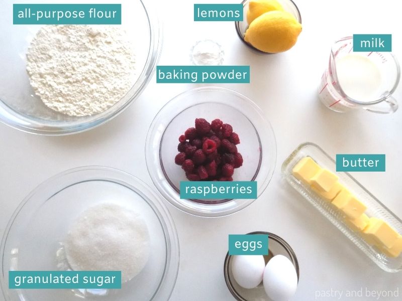 Ingredients for raspberry muffins on a white surface.