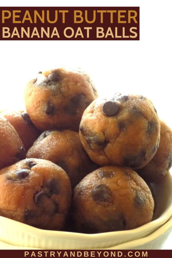 Peanut butter banana oat flour balls with chocolate chips randomly stacked in a white bowl.