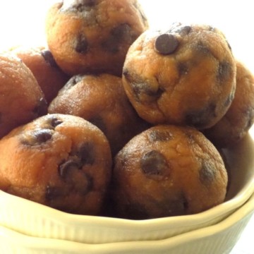 Peanut butter banana balls with chocolate chips randomly stacked in a white bowl.