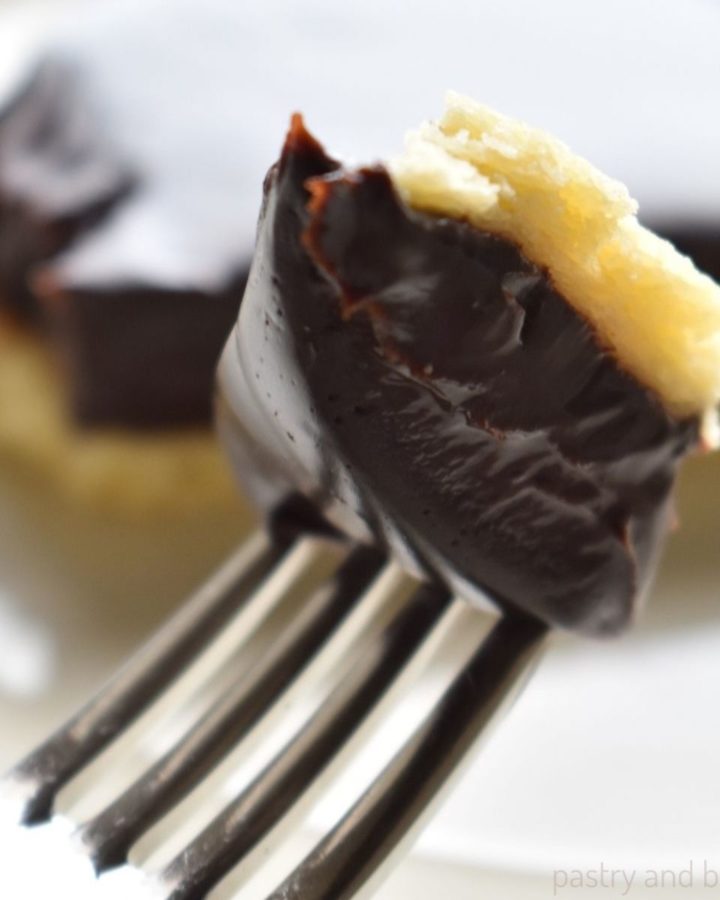 A piece of chocolate ganache tart on a fork, tart slice in the background.