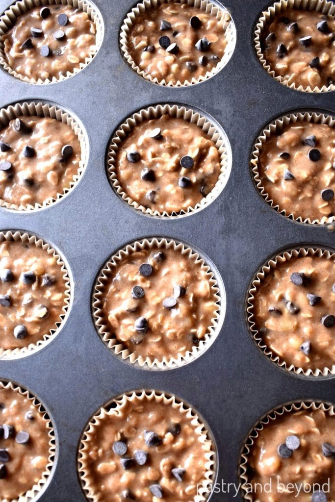 Banana oatmeal muffins batter with chocolate chips in a muffin pan.