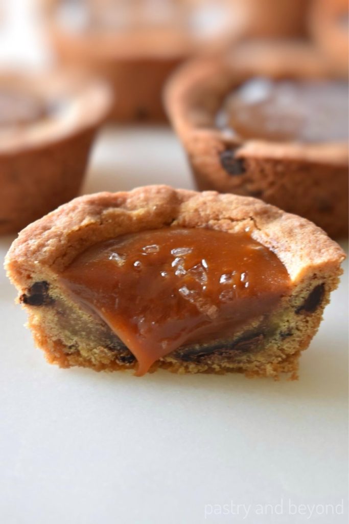 Half of chocolate chip cookie cup that is filled with caramel sauce and sea salt.
