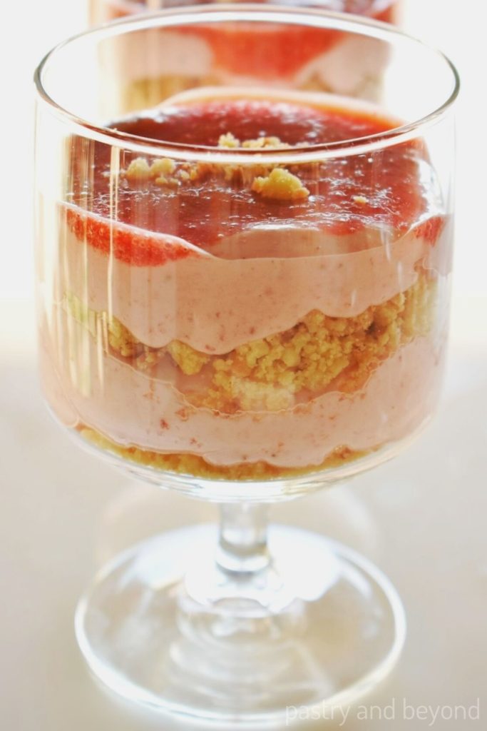 Layered strawberry mousse dessert in a pedestal glass cup. 