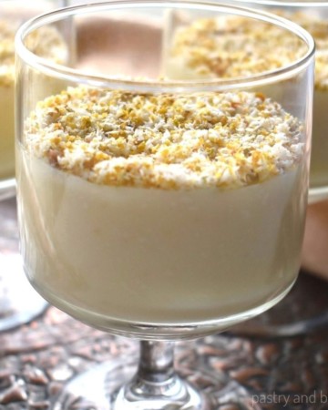 Almond pudding in serving glasses with ground pistachios and shedded coconut on top.