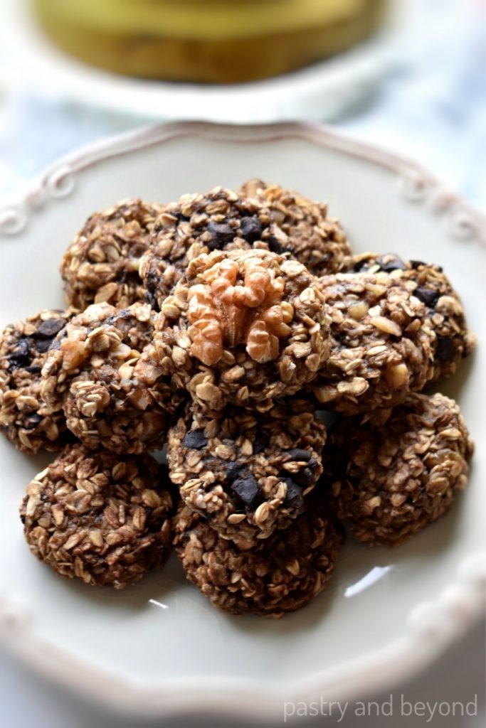Banana oatmeal cookies with walnuts, chocolate chips and cinnamon alternatives on a white plate.