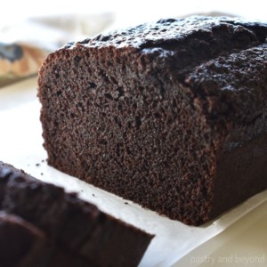 Chocolate loaf cake on a parchment paper with slices.