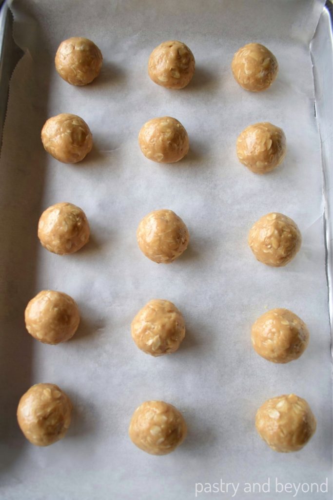 Peanut butter oatmeal balls on a parchment paper lined small baking sheet.