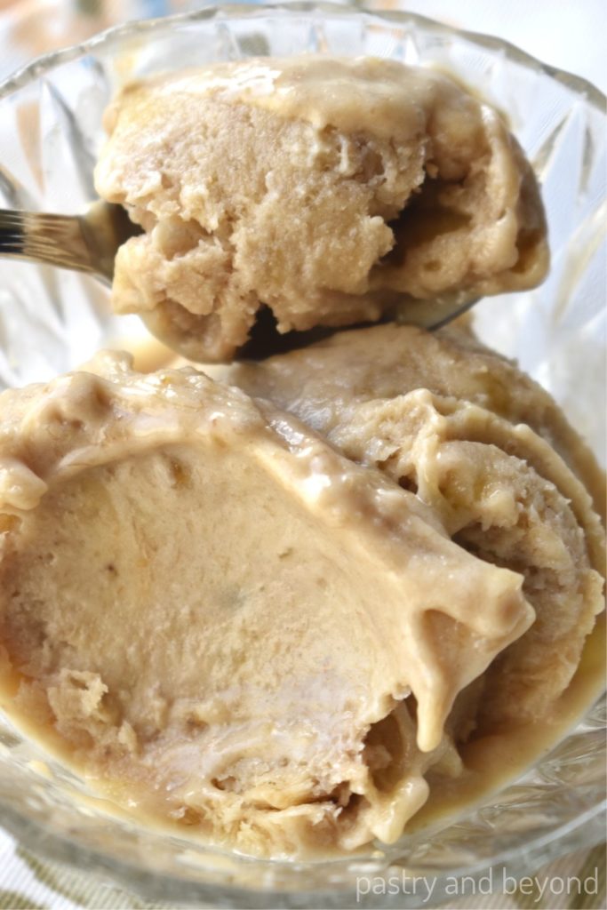 Peanut butter banana nice cream in a glass bowl with a spoon of ice cream.