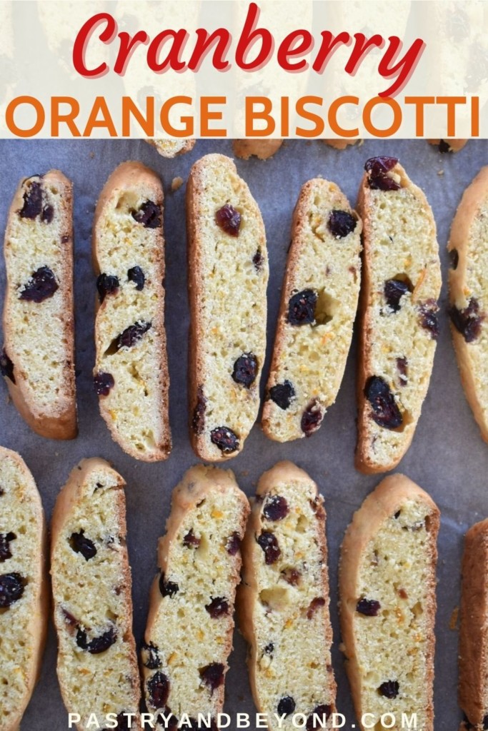 Cranberry orange biscotti cookies on a parchment paper with text overlay.