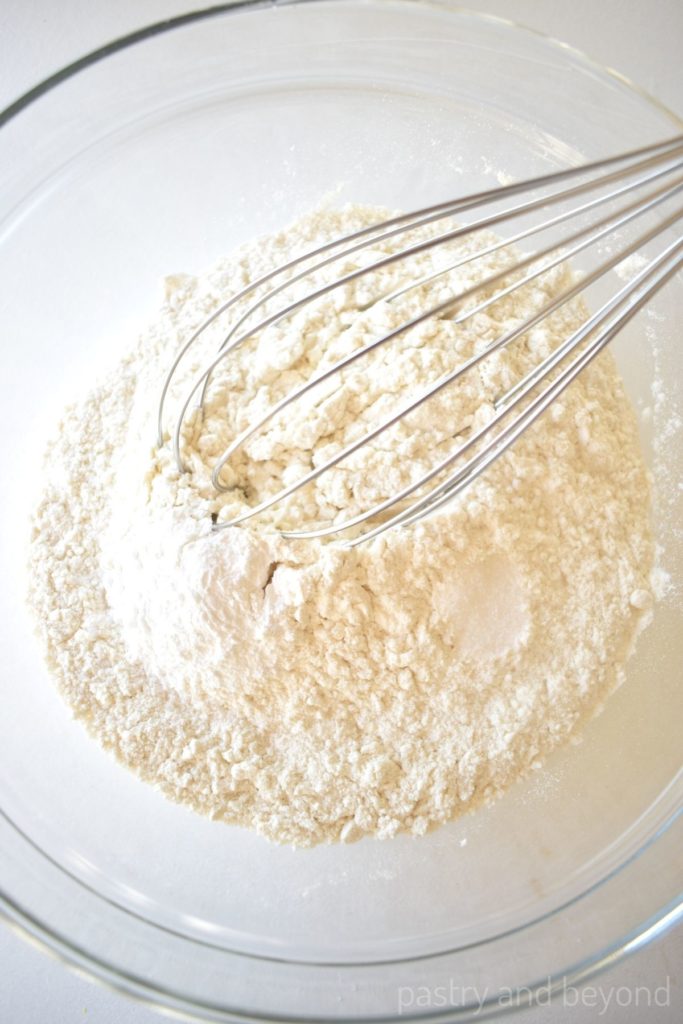 Flour and baking powder with a whisk in a bowl.