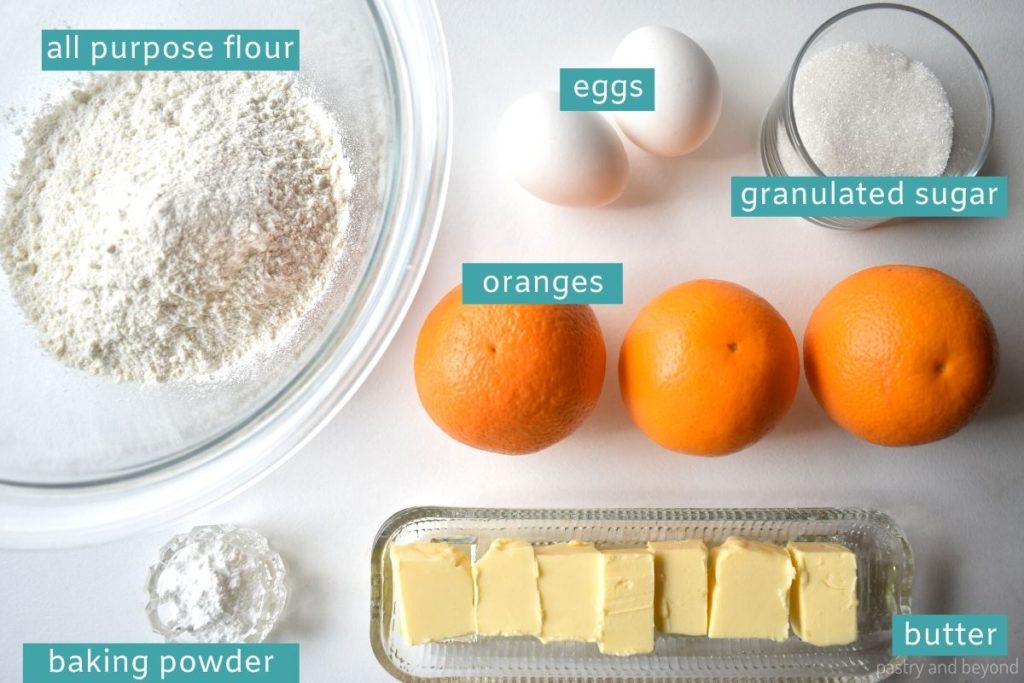 Ingredients for orange cake loaf on a white surface.