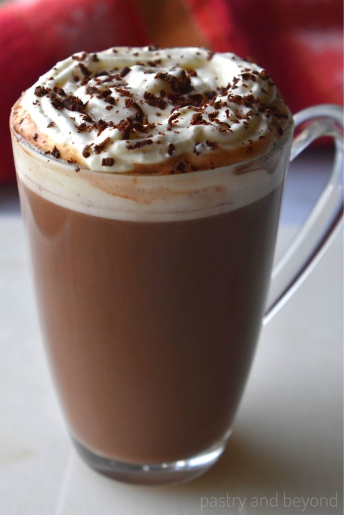 Hot chocolate on a white surface with whipped cream and grated chocolate on top.
