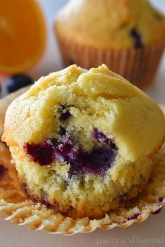 A bite taken from an orange blueberry muffin.
