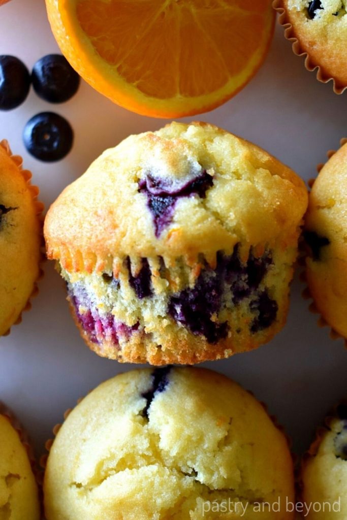 Orange blueberry muffins on a white surface.