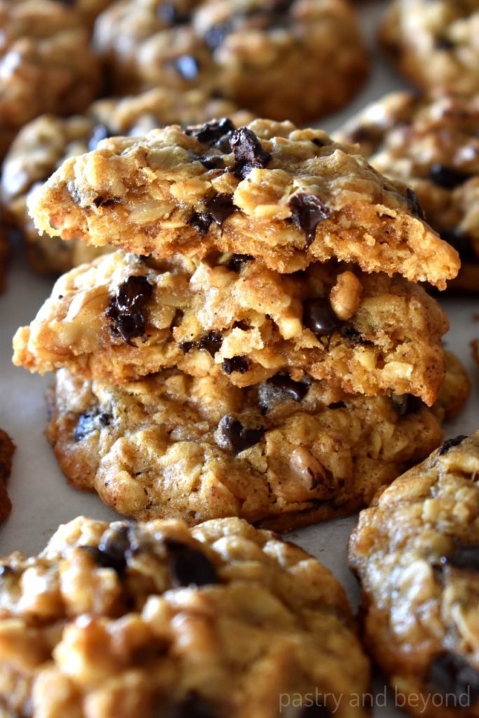 A bite taken stacked oatmeal chocolate chip cookies with walnuts.