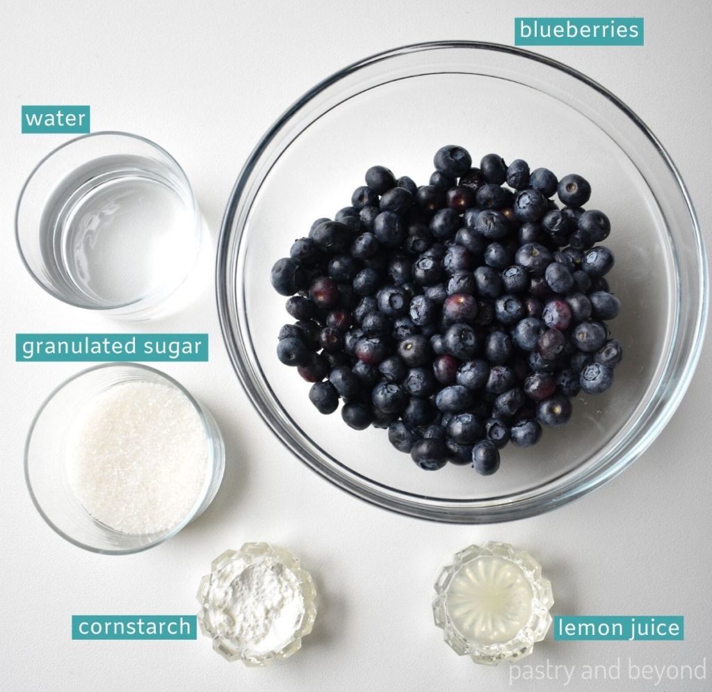 Ingredients for blueberry sauce on a white surface.