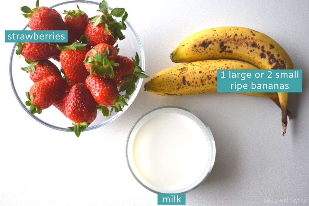 Ingredients to make strawberry banana smoothie without yogurt on a white surface.