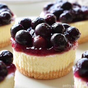 Mini blueberry cheesecakes on a serving plate.