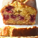 Raspberry and white chocolate loaf cake on a white surface.
