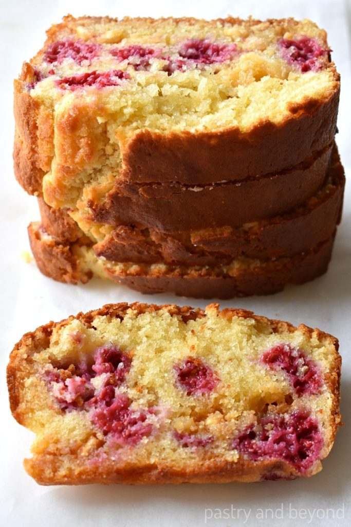 Stacked raspberry and white chocolate loaf cake slices.