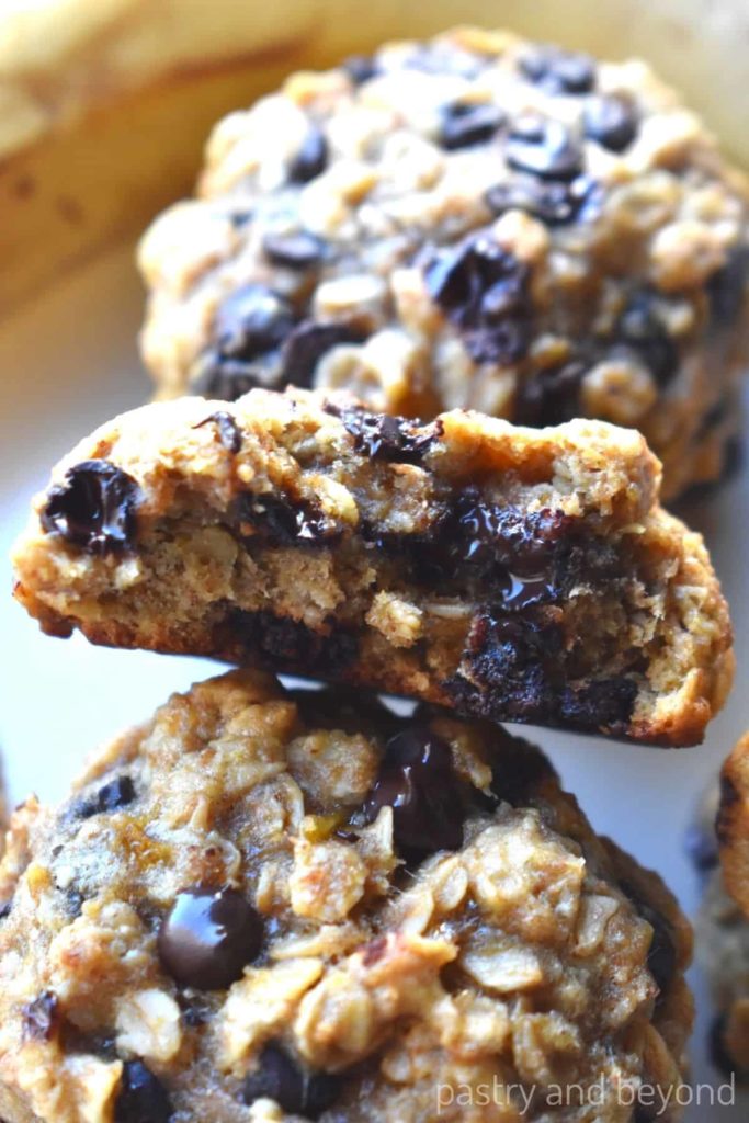 Banana oatmeal chocolate chip cookie that is cut in half between two cookies.