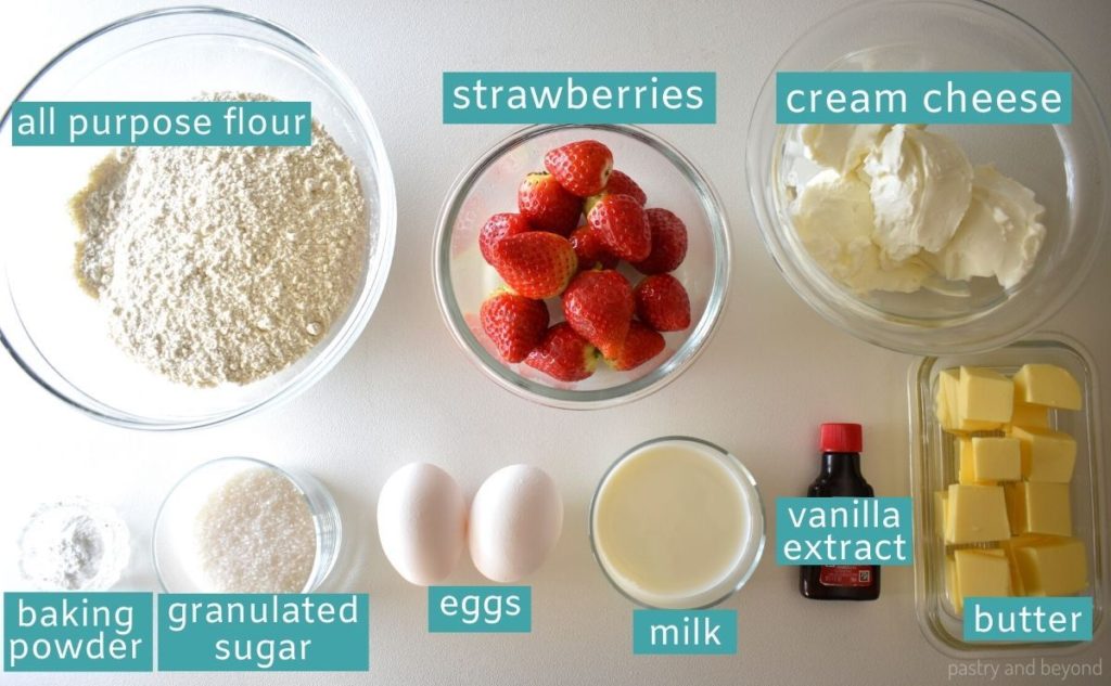 Ingredients to make strawberry cream cheese muffins on a white surface.