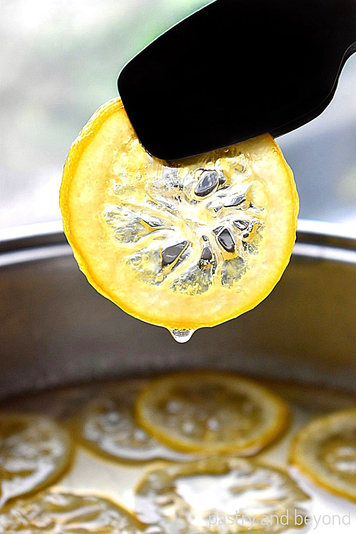 Holding candied lemon slice with tongs.