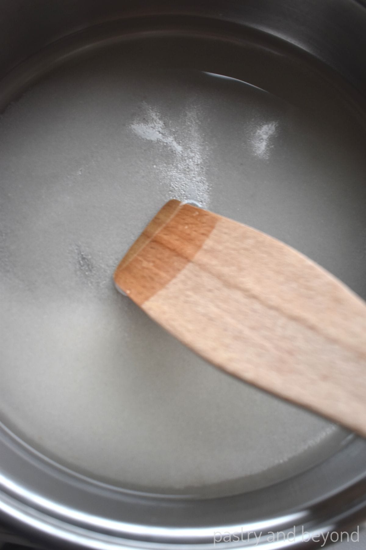 Stirring sugar and water in a pan with a spatula.