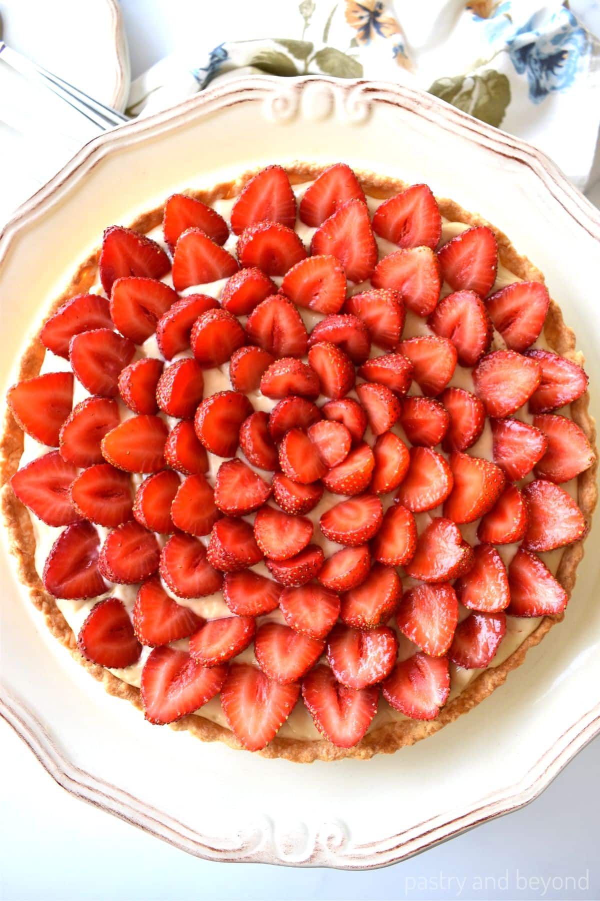Strawberry custard tart on a cake stand.