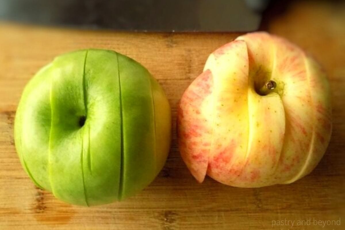 Sliced green and red apple on a chopping board.