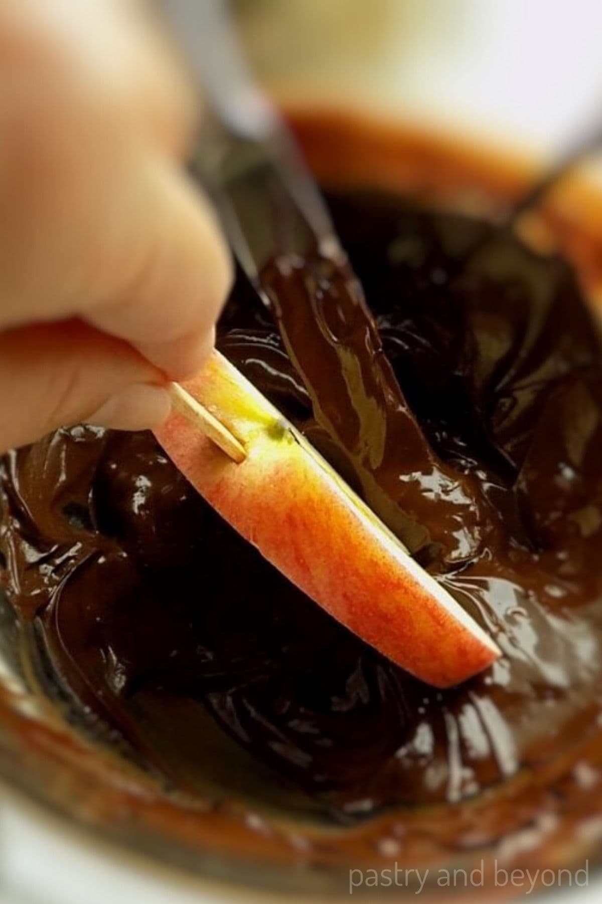 Dipping the apple into melted chocolate.