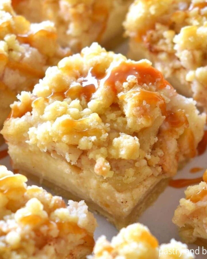 Apple cheesecake bars on a white surface.