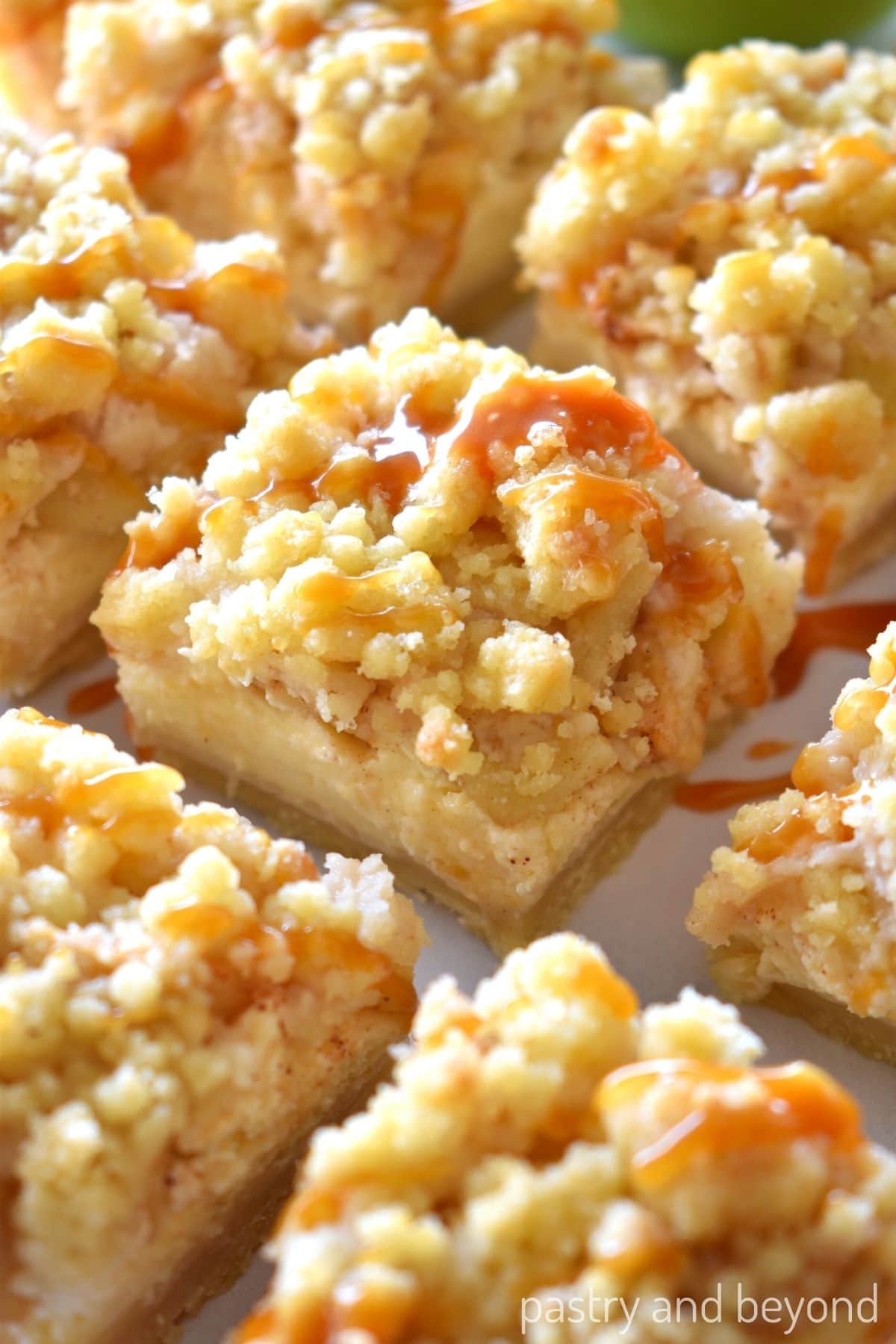 Apple cheesecake bars on a white surface.