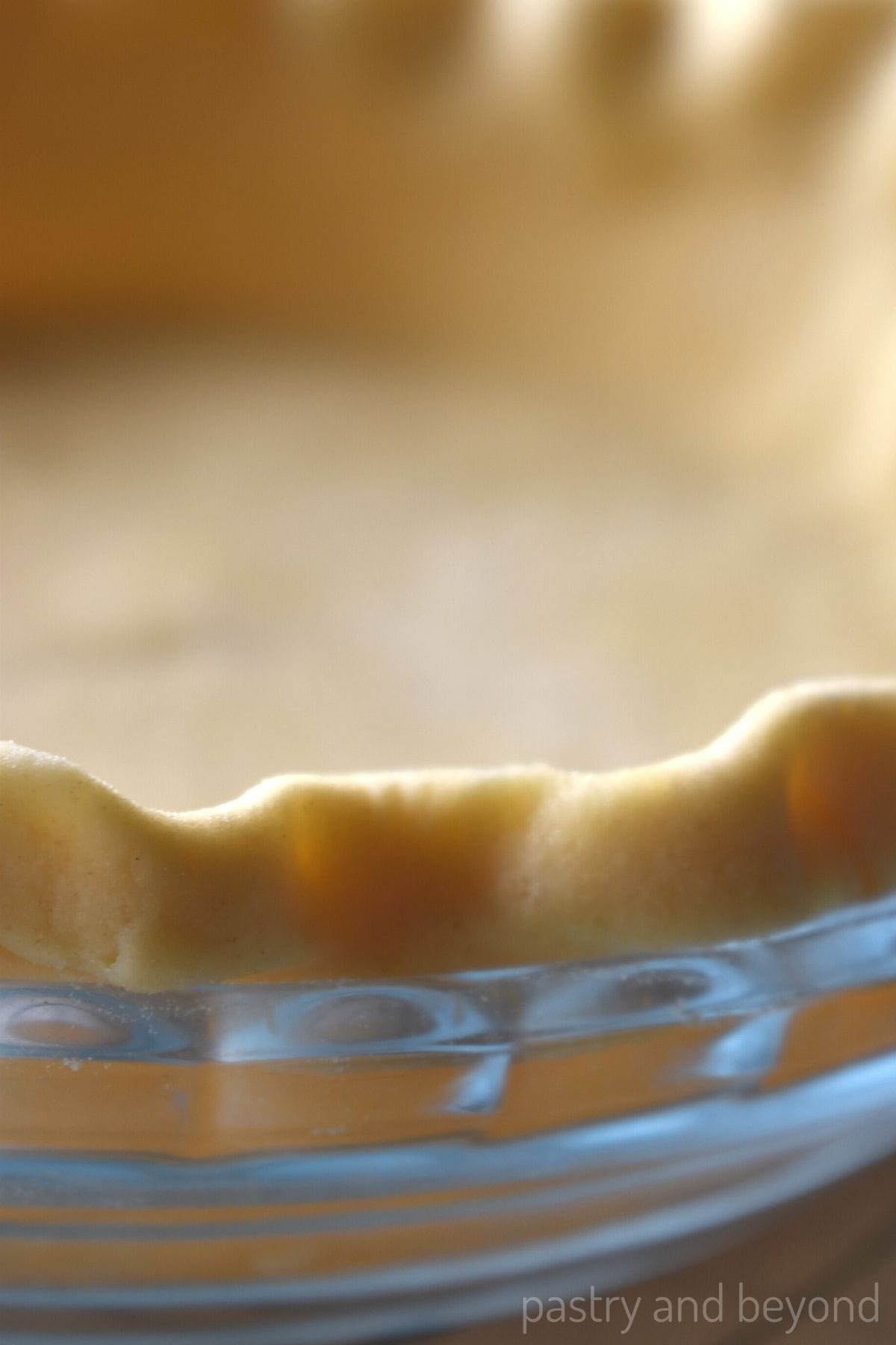 Pie dough on a pie dish with a fluted edge.