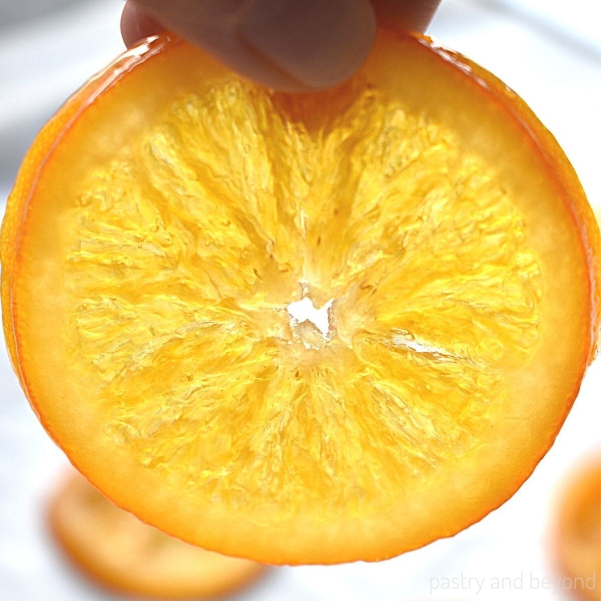 A hand holding a candied orange slice.