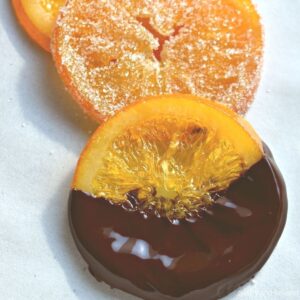 Chocolate covered, sugar coated and plain candied orange slices on a parchment paper.