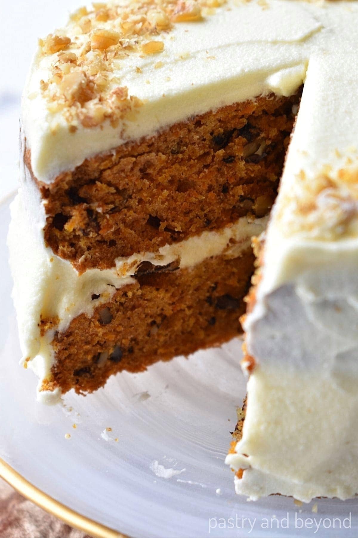 Mini carrot cake on a cake stand with a slice taken from it.