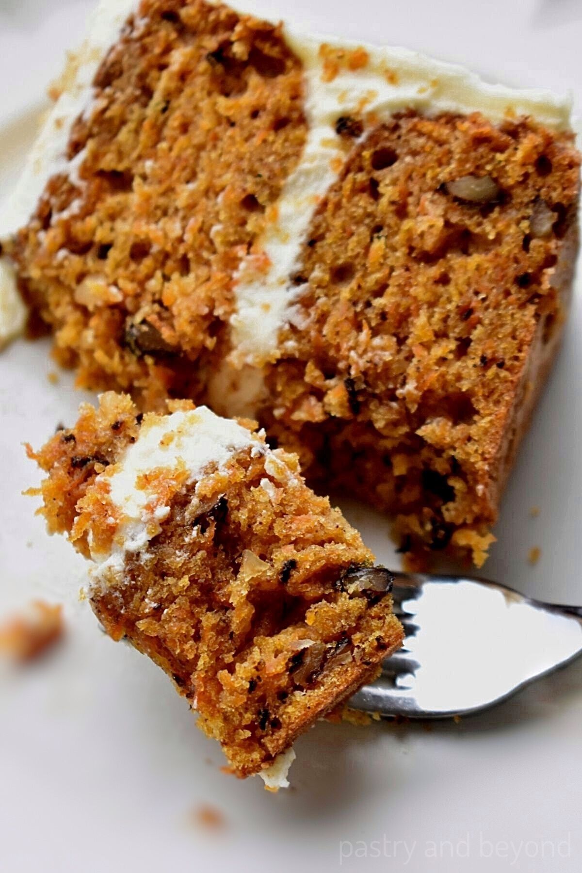 Carrot cake on a plate with a bite taken.