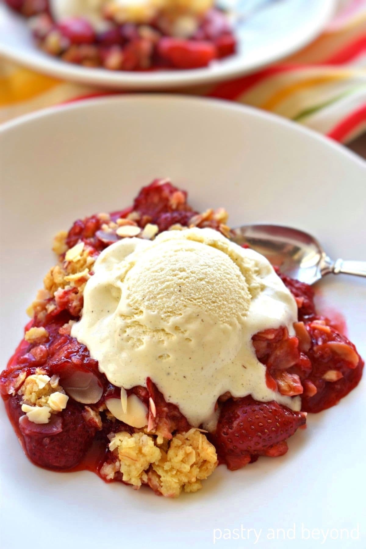 Strawberry crumble with vanilla bean ice cream on a plate.