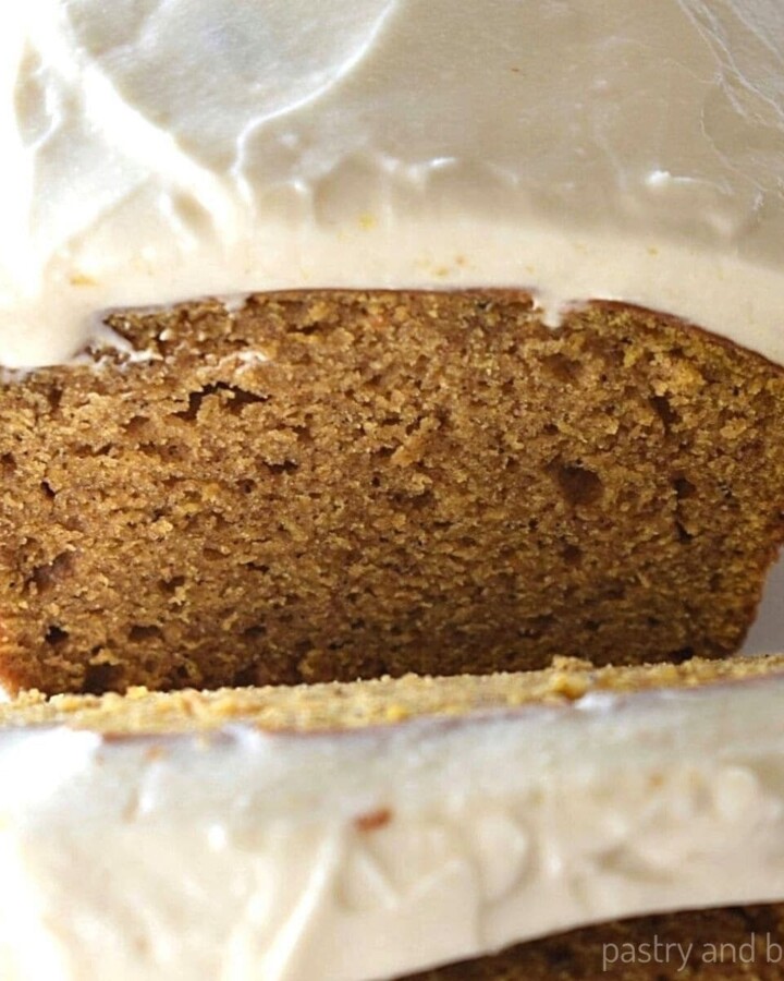 Cream cheese frosted pumpkin loaf with slices.