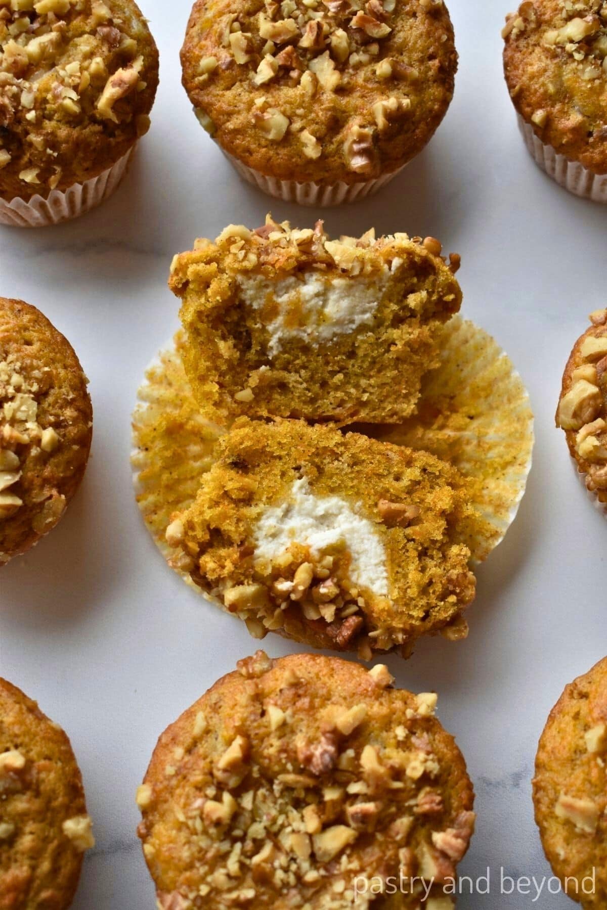 Carrot cake cream cheese filled muffin that is cut in half, in the middle of other muffins.