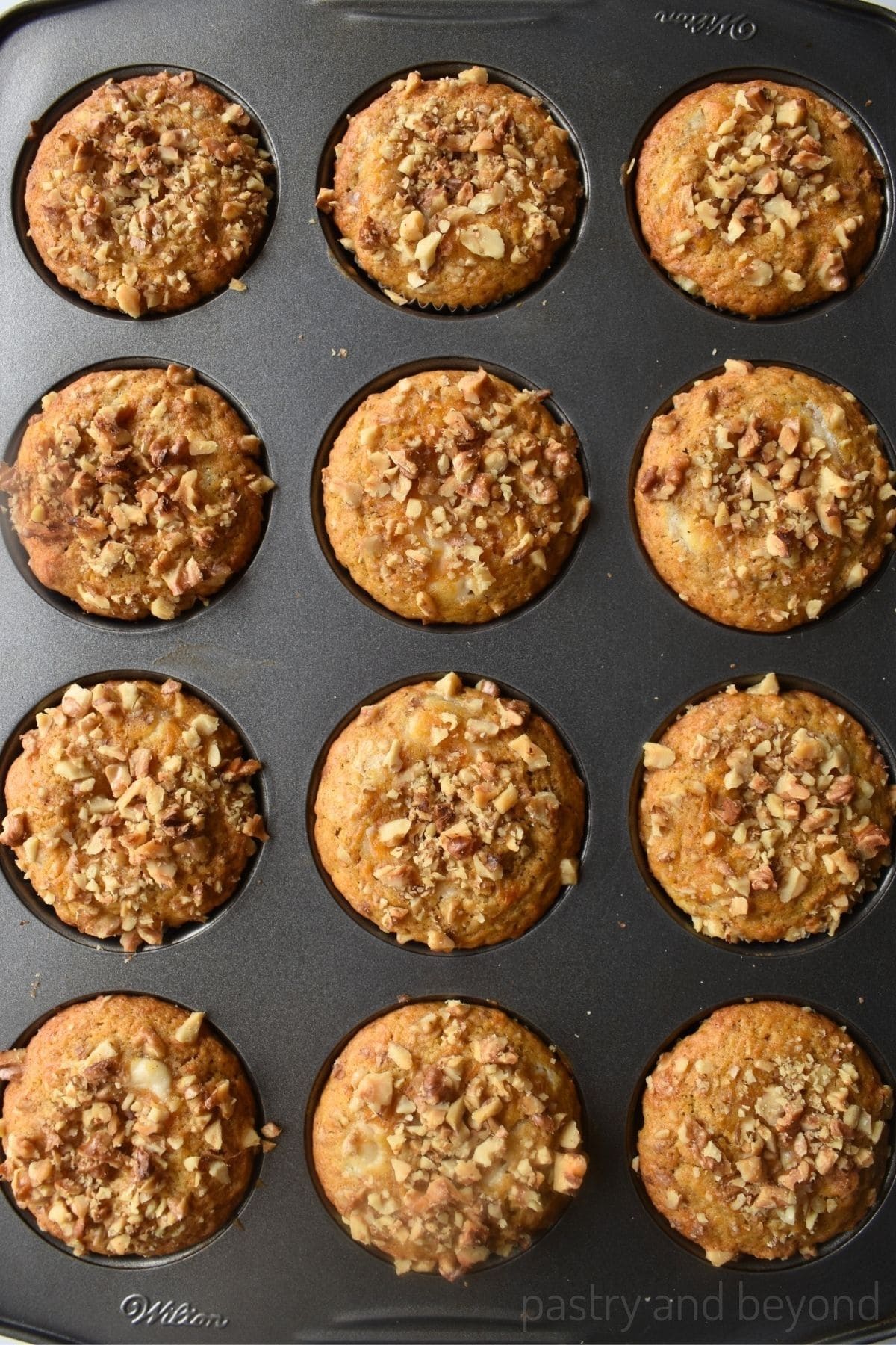 Carrot cake cream cheese muffins in a muffin pan.